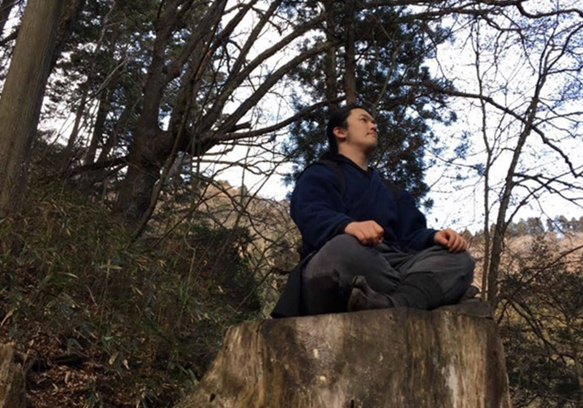 山中の切株で息長を行う男性